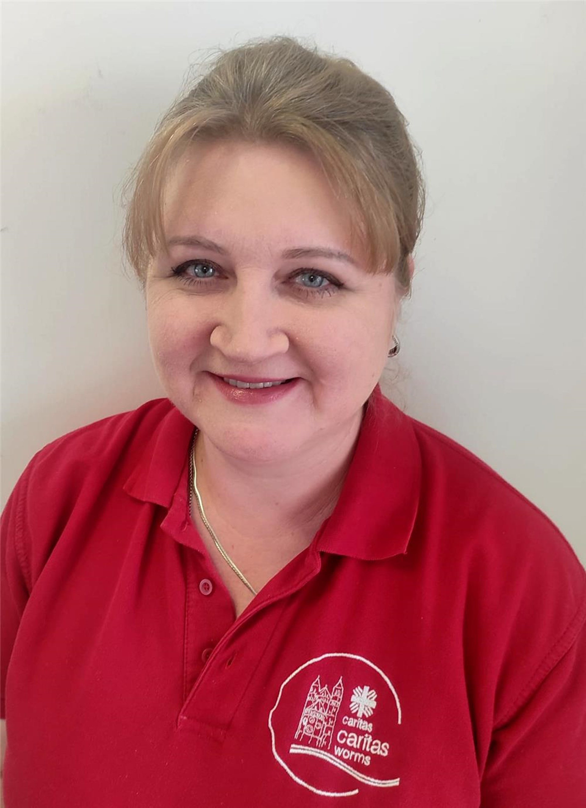 Portrait Frau Olesya Mayer in rotem Caritas-T-Shirt mit Logo