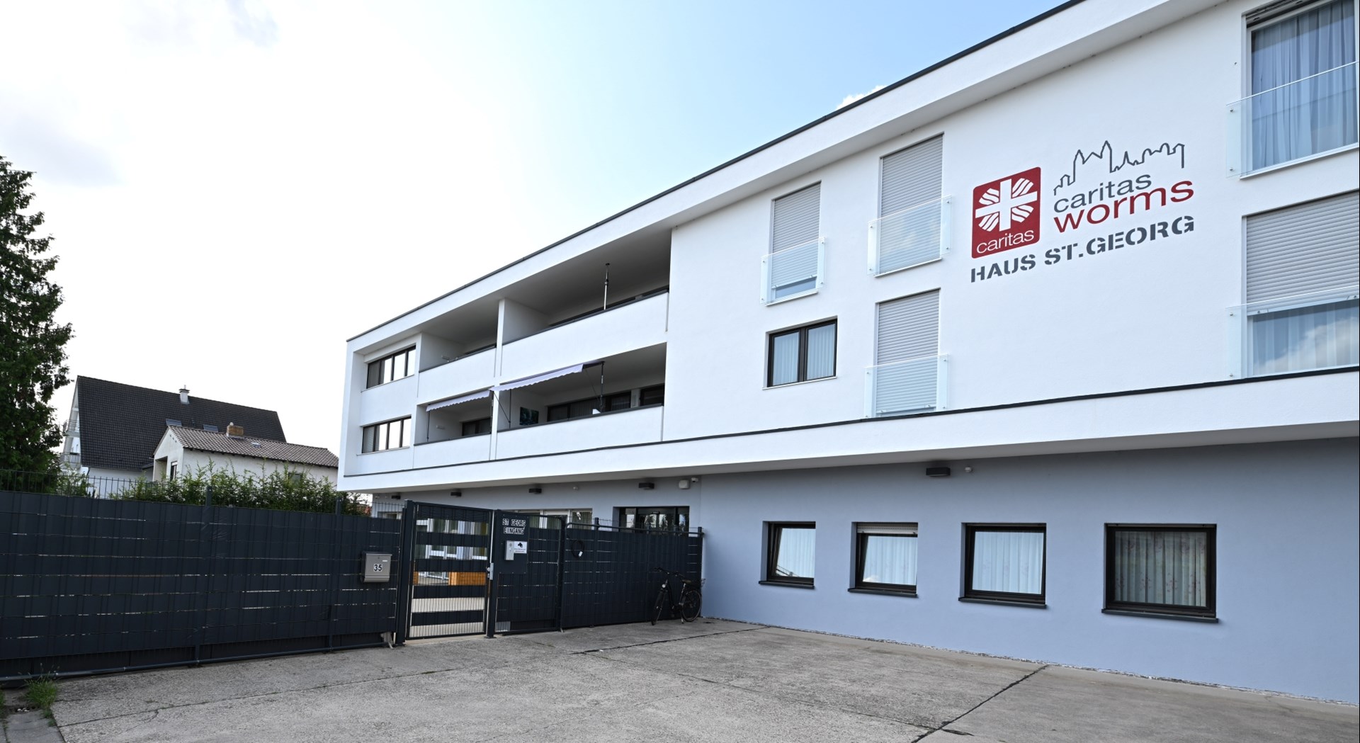 Außenansicht des Caritas Worms Haus St. Georg: modernes, mehrstöckiges Gebäude in heller Fassade mit Balkonen und gut sichtbarem Caritas-Logo am Eingang.