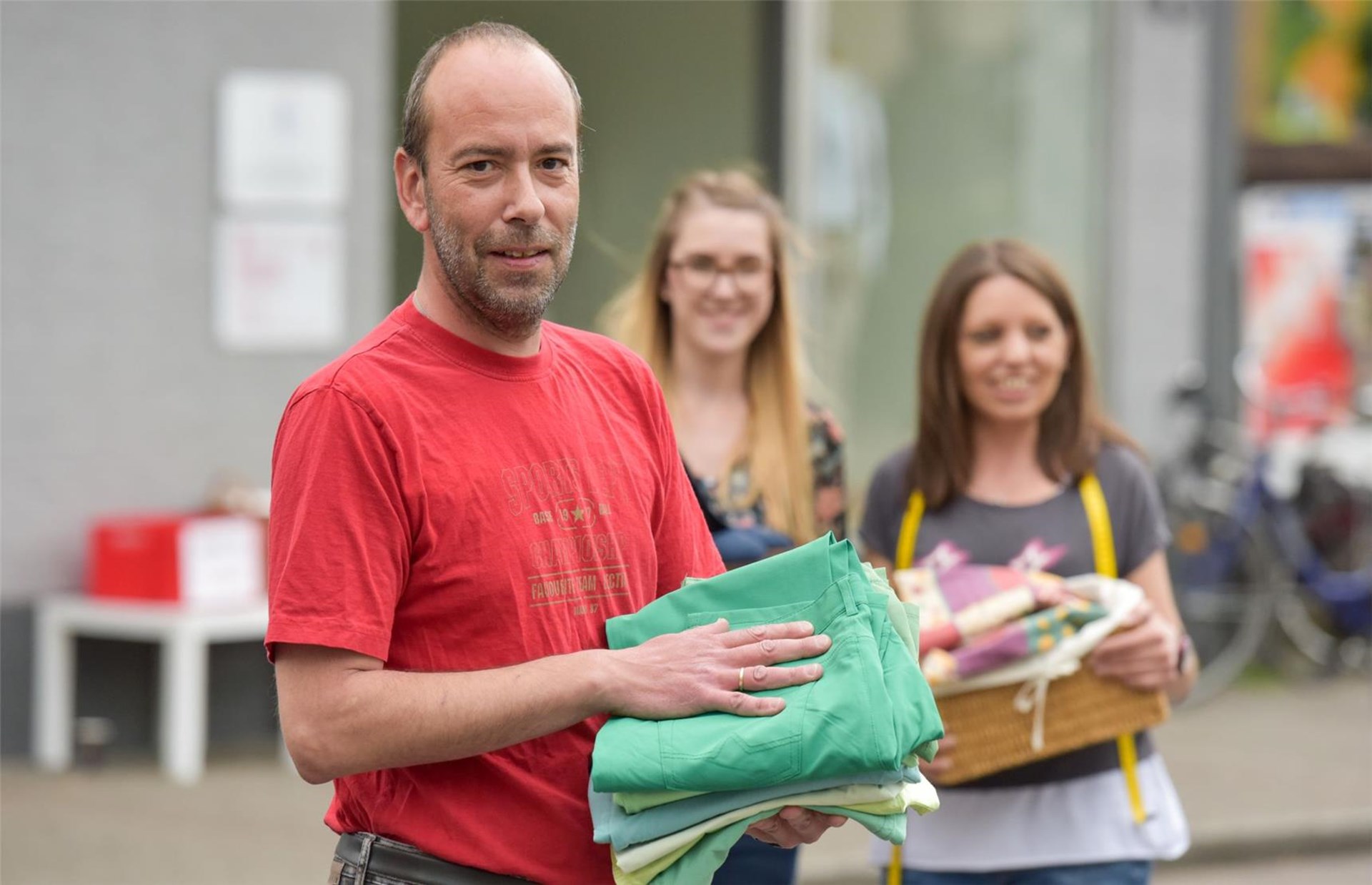 Menschen vor der Kleiderkammer mit Kleidern in der Hand
